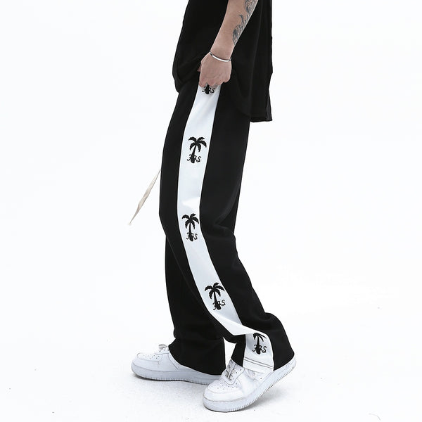 track pants, athleisure pants, casual style, streetwear, palm tree print, side stripe, relaxed fit, men's fashion, tropical design, trendy pants, comfortable fit, breathable fabric, lounging pants, versatile pants, everyday wear, island-inspired, soft fabric, stylish track pants, athletic-inspired, men’s casual pants, bold stripe, cool outfit, men’s wardrobe essential, statement pants, urban fashion