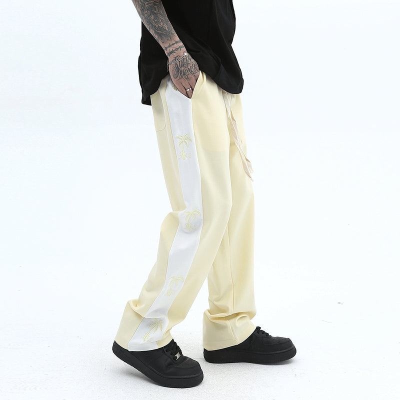 track pants, athleisure pants, casual style, streetwear, palm tree print, side stripe, relaxed fit, men's fashion, tropical design, trendy pants, comfortable fit, breathable fabric, lounging pants, versatile pants, everyday wear, island-inspired, soft fabric, stylish track pants, athletic-inspired, men’s casual pants, bold stripe, cool outfit, men’s wardrobe essential, statement pants, urban fashion
